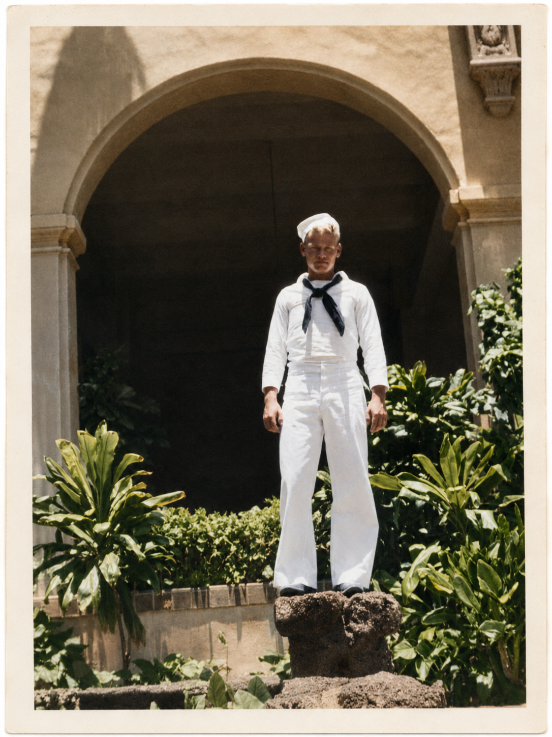 Frank McCammon Jr. in U.S. Navy dress whites, standing in a tropical garden in Hawaii